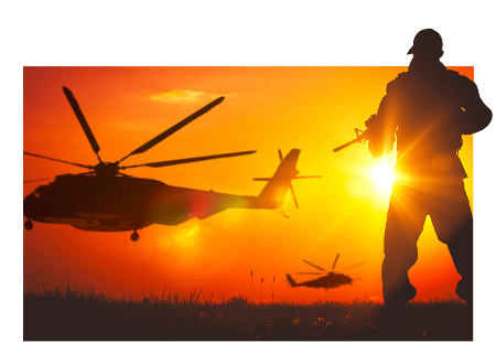 Soldier and helicopter silhouetted against a sunset