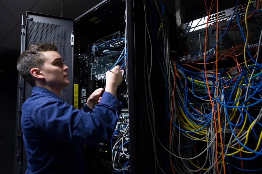Information systems technician adjusting cables in a server rack